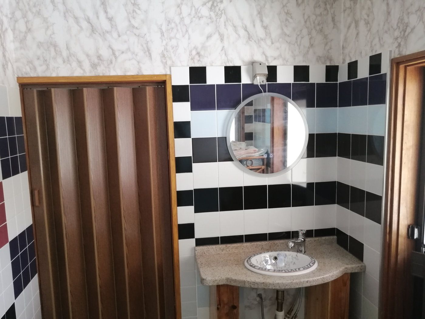 Bathroom with tiled walls and round mirror